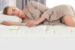 a woman sleeping on a mattress topper
