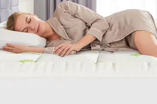 a woman sleeping on a mattress topper