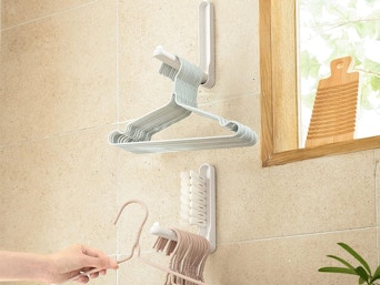 a woman putting hangers on a storage hook