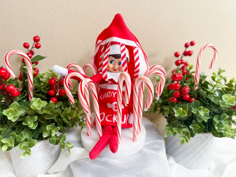 elf on the shelf doll in costume in diy candy cane jail 