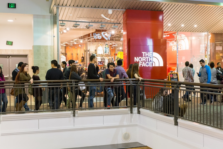 a crowd of people outside a north face store in mall 