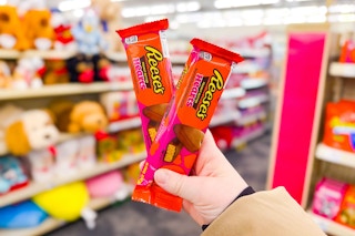 person holding 2 packs of reese's peanut butter hearts