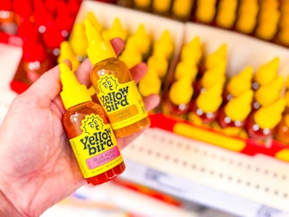 hand holding 2 yellowbird hot sauces in front of a target shelf