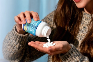 woman empty supplements into hand