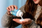 woman empty supplements into hand