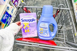 person placing snuggle dryer sheets in a cart with fabric softener