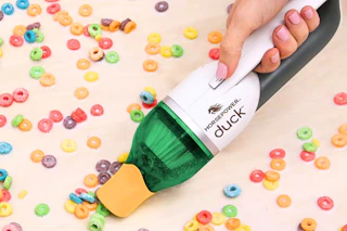 Lifestyle image of the Horsepower Duck handheld vacuum used to clean up spilt cereal