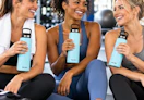 3 women in a gym with holding blue water bottles