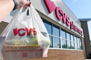 hand holding a cvs shopping bag in front of a cvs store