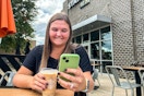 a person holding coffee and looking at their phone outside of starbucks