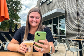 a person sitting at a table at starbucks looking at their phone