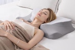 woman laying on grey/white cervical neck pillow