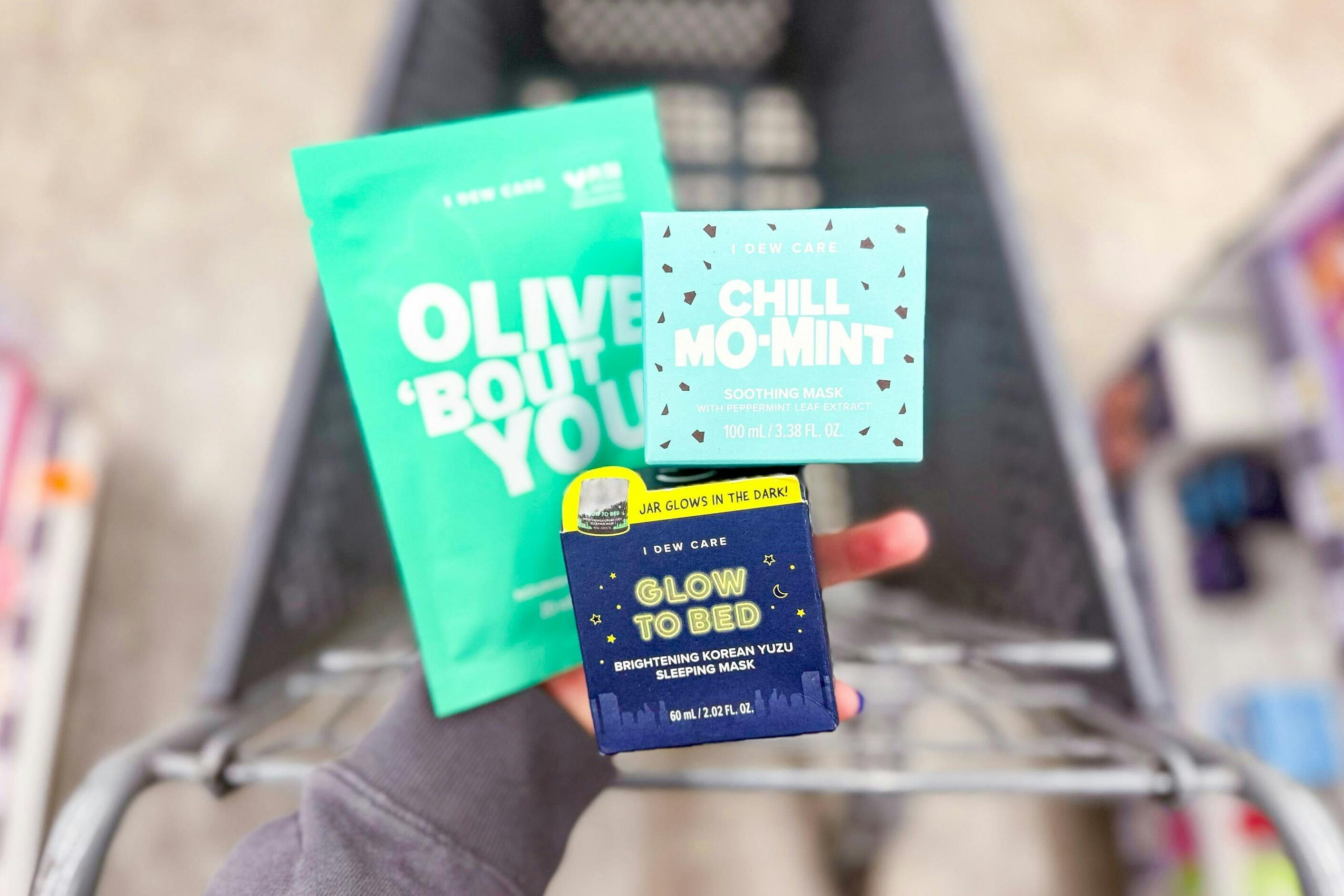 hand holding i dew care skincare products over a shopping cart