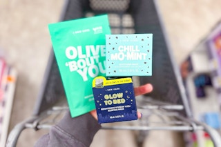 hand holding i dew care skincare products over a shopping cart