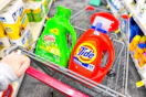 person pushing a cart with large bottles of tide and gain detergent in it
