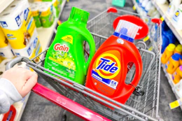 person pushing a cart with large bottles of tide and gain detergent in it
