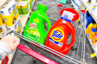 person pushing a cart with large bottles of tide and gain detergent in it