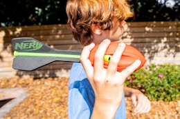 a person holding foam Nerf football outside