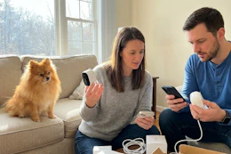 a couple unboxing arlo cameras near a pomeranian