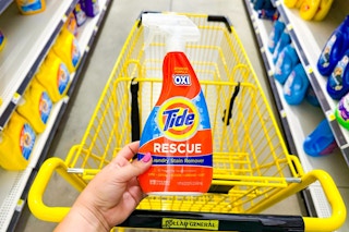 hand holding a bottle of tide rescue above a dollar general shopping cart