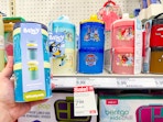 hand holding a bluey whiskware stackable food jar set in front of a shelf