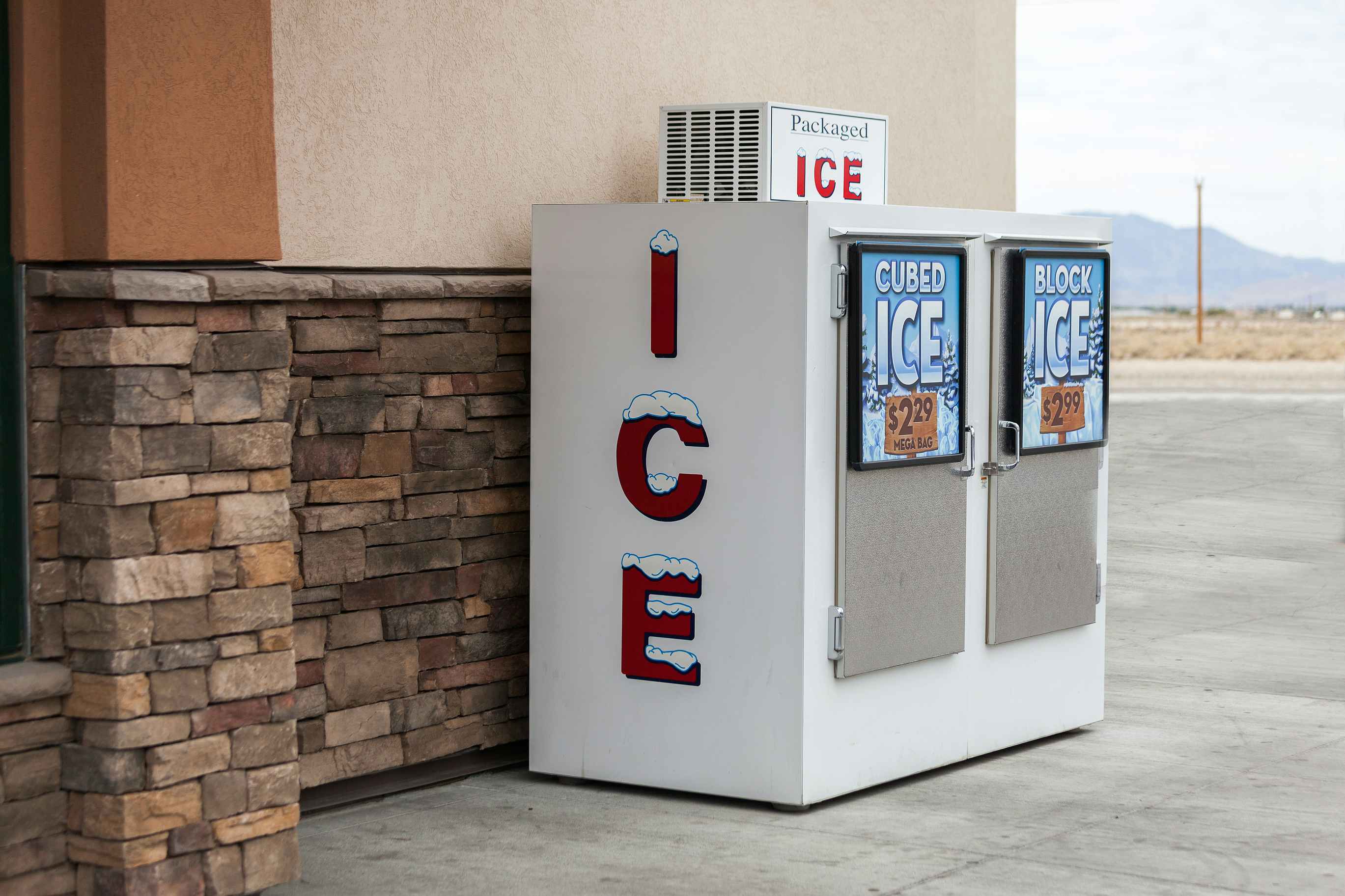 Photo of an ice machine outside a grocery store, with a sign reflecting a "Mega Bag" price of $2.29.