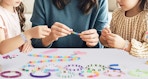 a mom and daughters making beaded bracelets