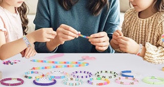 a mom and daughters making beaded bracelets
