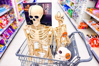 halloween decorations in a cart including a posable skeleton, skull, and small skeleton
