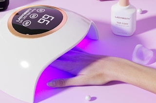 a woman using a uv gel nail lamp on a table