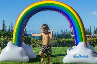 a kid outside playing with a giant rainbow sprinkler