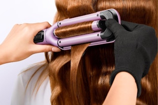 a woman using a wavytalk curling iron on a woman's hair