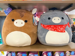 Two large Squishmallows, a horse and a donkey, on a shelf at BoxLunch