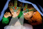children reading a book wearing a dinosaur headlamp