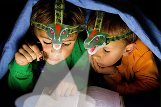 children reading a book wearing a dinosaur headlamp