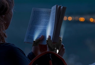 a person using flashlight gloves while reading a book