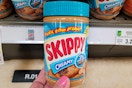 hand holding a jar of skippy peanut butter 