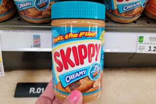 hand holding a jar of skippy peanut butter 