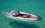 a person laying on a paddle board in the ocean