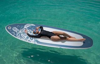 a person laying on a paddle board in the ocean