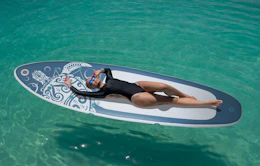 a person laying on a paddle board in the ocean
