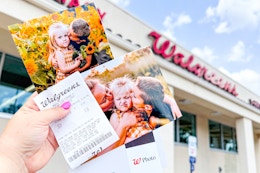 someone holding up some free photo prints they got at walgreens
