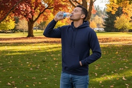 a man drinking from a water bottle in a park