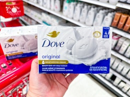 hand holding a dove bar soap 4-pack in front of parked target cart