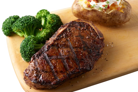 A Smokey Bones 6 oz steak with broccoli and baked potato on a plate.