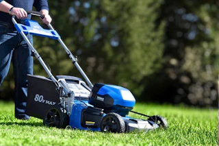 Lifestyle image of a Kobalt Push Mower being used to cut grass
