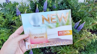 Woman holding Bath and Body Works mailer in garden
