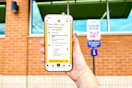 hand in front of a walgreens pickup sign holding a smartphone displaying a kcl app 1-clip deal