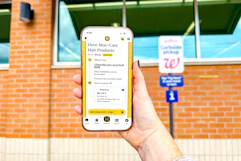 hand in front of a walgreens pickup sign holding a smartphone displaying a kcl app 1-clip deal