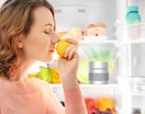 a person smelling a lemon in a fridge next to a deodorizer